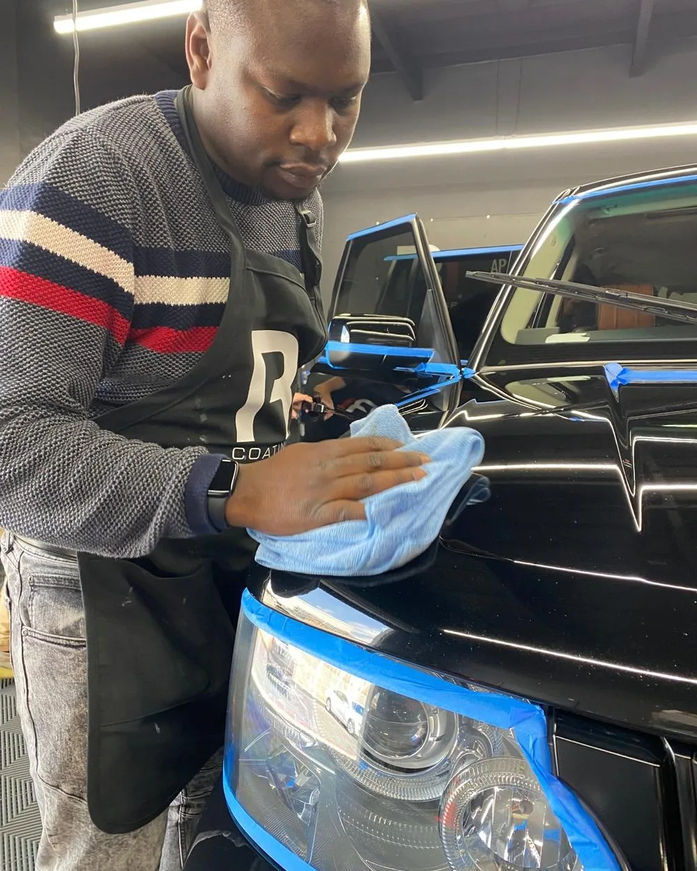 Baby Blanket technician hand-polishing the hood of a black Range Rover in the Seattle shop