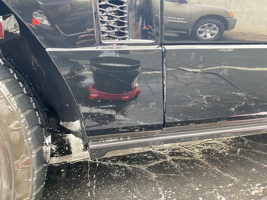 Exterior decontamination wash in progress on a dark vehicle