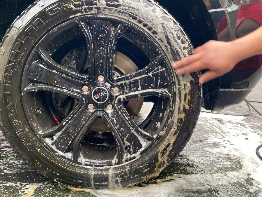 Alloy wheel and brake caliper being cleaned with detailing brushes